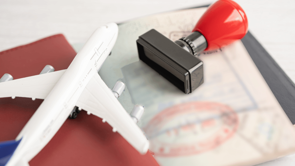 Passport with visa stamps, red stamp tool, and toy airplane symbolizing travel and visa extensions.