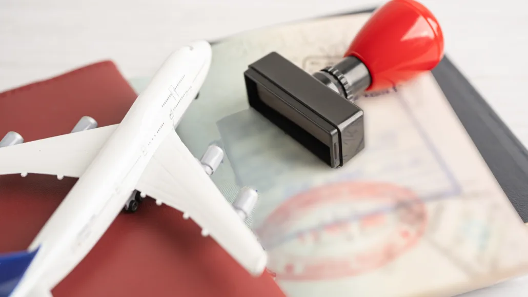 Passport with visa stamps, red stamp tool, and toy airplane symbolizing travel and visa extensions.