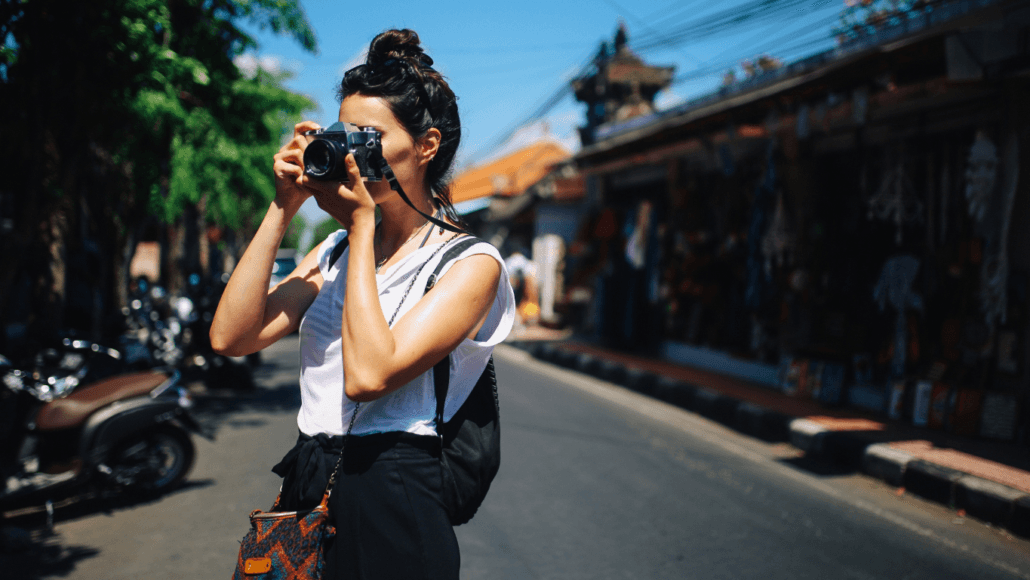 A tourist exploring Seminyak street markets with a camera, capturing the vibrant street food scene.