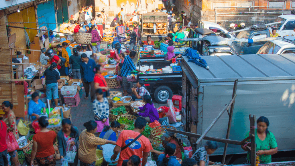 Crowds exploring a vibrant street food market in Seminyak, filled with stalls and colorful ingredients.