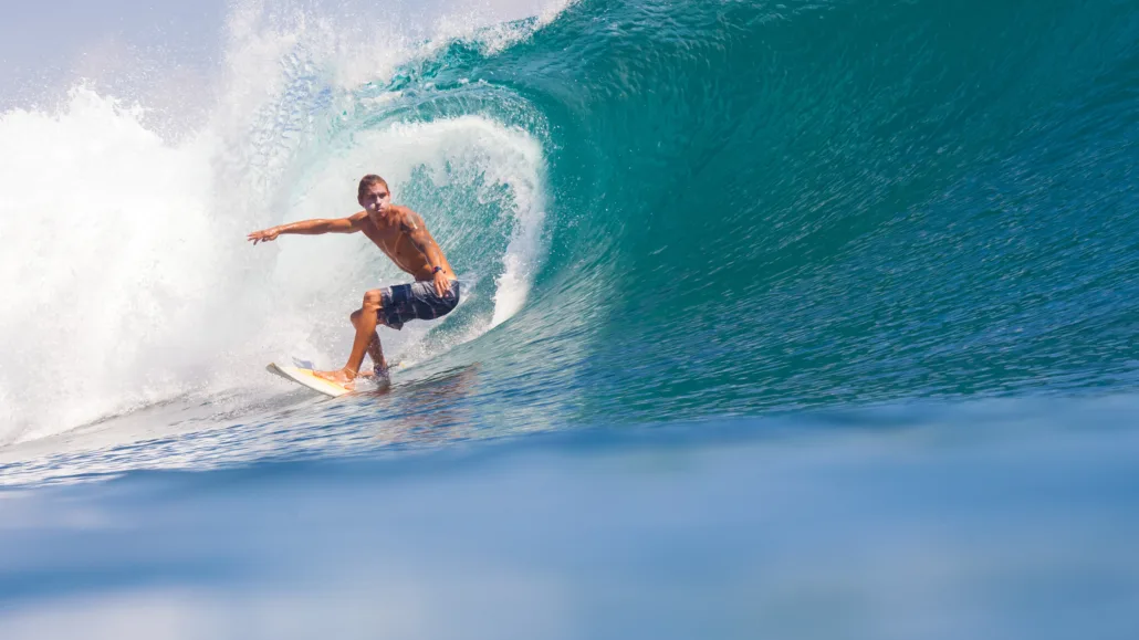 A Male Surfer riding a perfect wave in Seminyak beach.