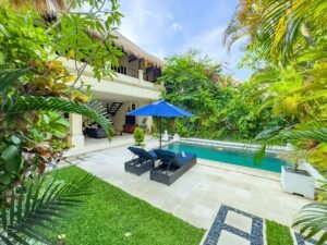 Private pool area of a 3 bedroom villa in Seminyak, featuring sun loungers, lush garden views, and a modern tropical design.