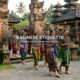 Tourists wearing traditional sarongs while visiting a Balinese temple and respecting local customs in Bali