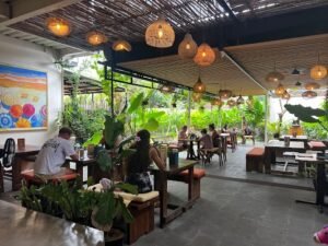 Cozy and tropical seating area inside Bloom Cafe Seminyak, surrounded by lush plants and natural lighting