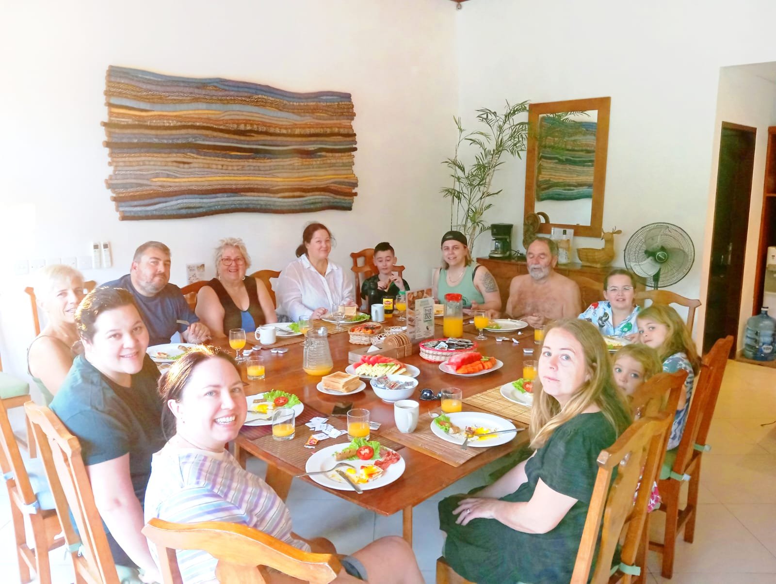 A family with children enjoying a fresh morning breakfast together at a large wooden dining table inside Villa Alore Seminyak.