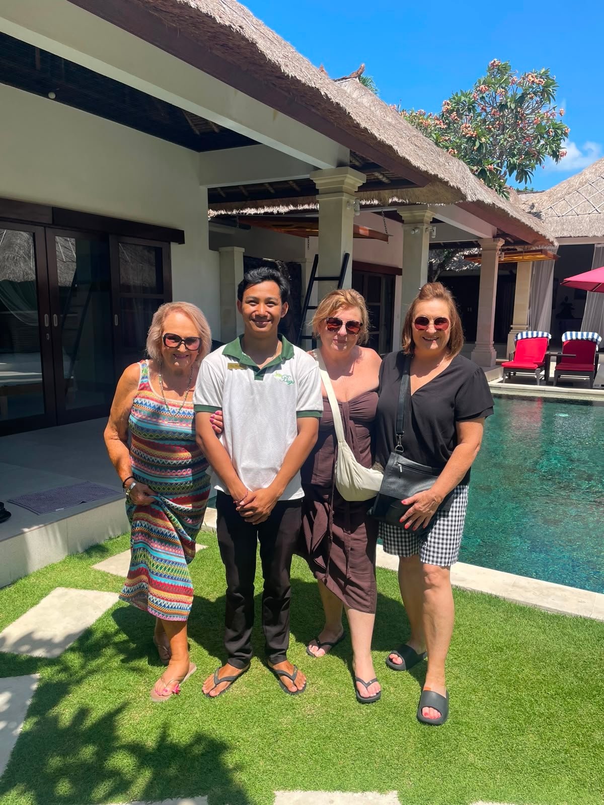 Three female guests posing for a group photo with a welcoming villa staff member next to the private swimming pool at Villa Rama.