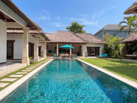 Long private pool with stone decking and tropical palms at a Villa Bugis villa