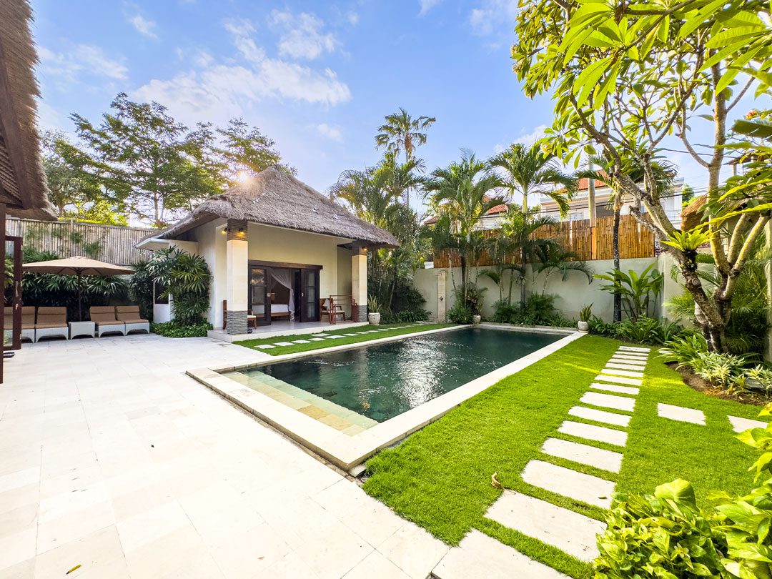 Manicured lawn and tropical palm trees enclosing the private pool at Villa Alore Seminyak by Villa Bugis villa Seminyak.