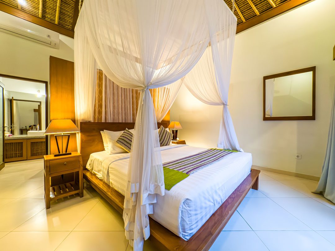Warm wooden accents and cozy interior design in king bedroom 5 at Villa Alore Seminyak by Villa Bugis Seminyak villas.