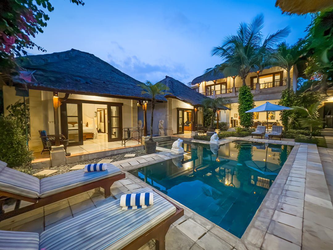 Serene evening ambiance with warm lighting reflecting on the private swimming pool at Villa Arjuna Seminyak by Villa Bugis Seminyak villas.