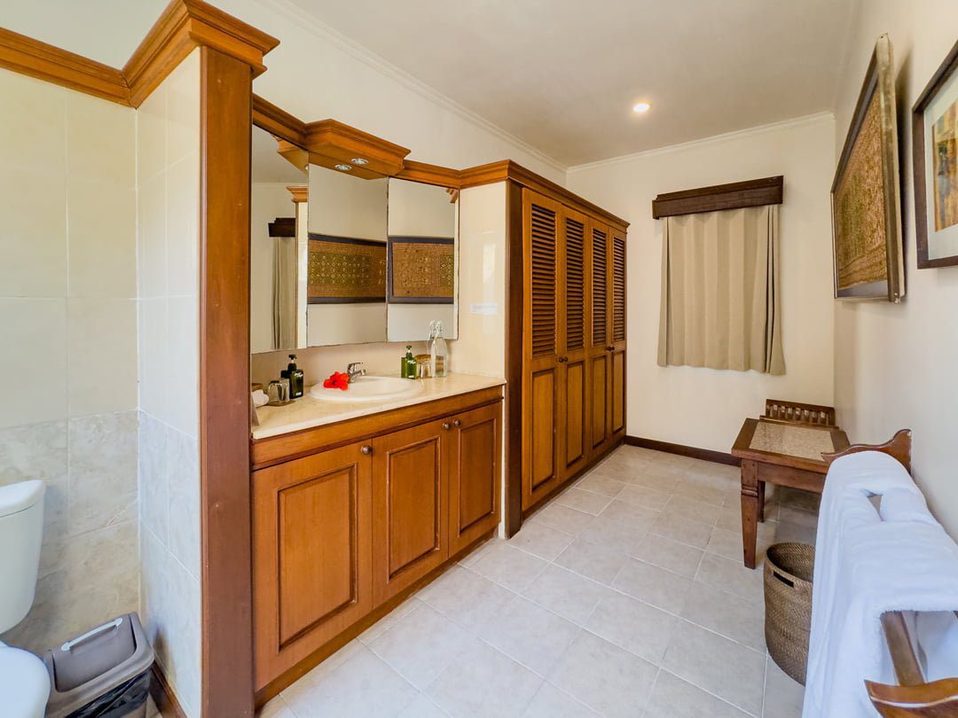 Pristine shower area enclosed by natural stone textures and plants in the bathroom of bedroom 2 at Villa Arjuna Seminyak by Villa Bugis Seminyak villas.
