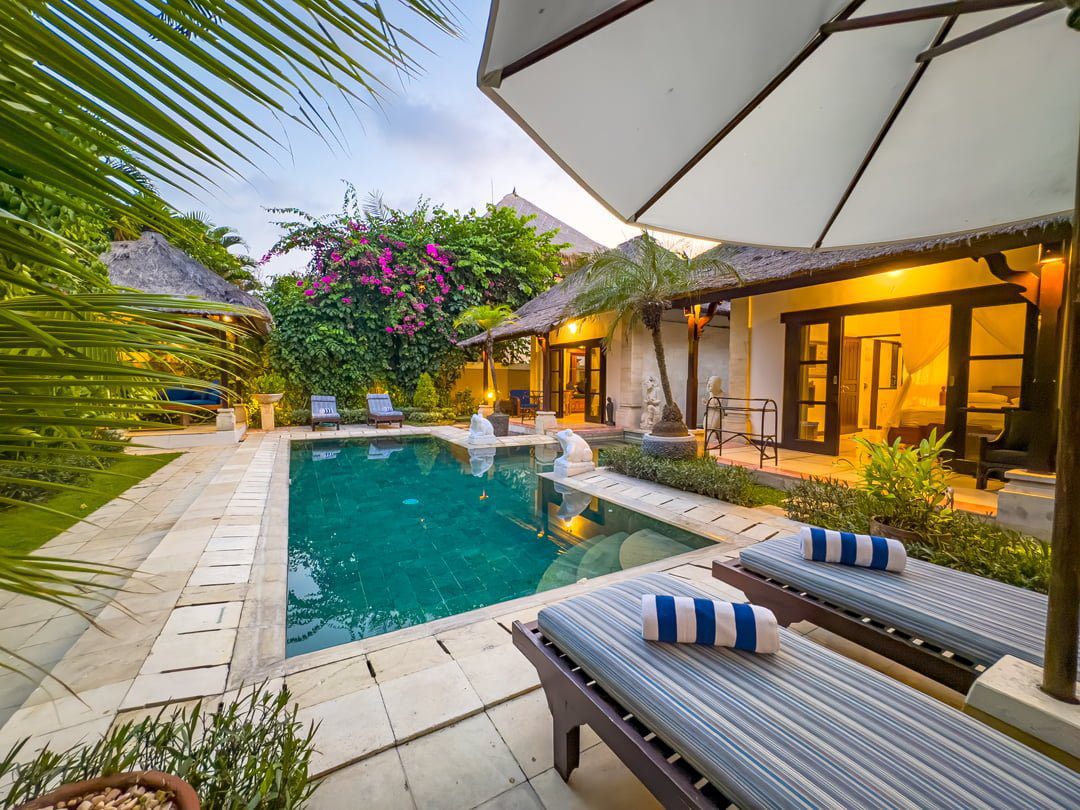 Spacious poolside lounge area lit by warm ambient lighting at Villa Arjuna Seminyak by Villa Bugis, ideal for families looking for a premium villa Seminyak.