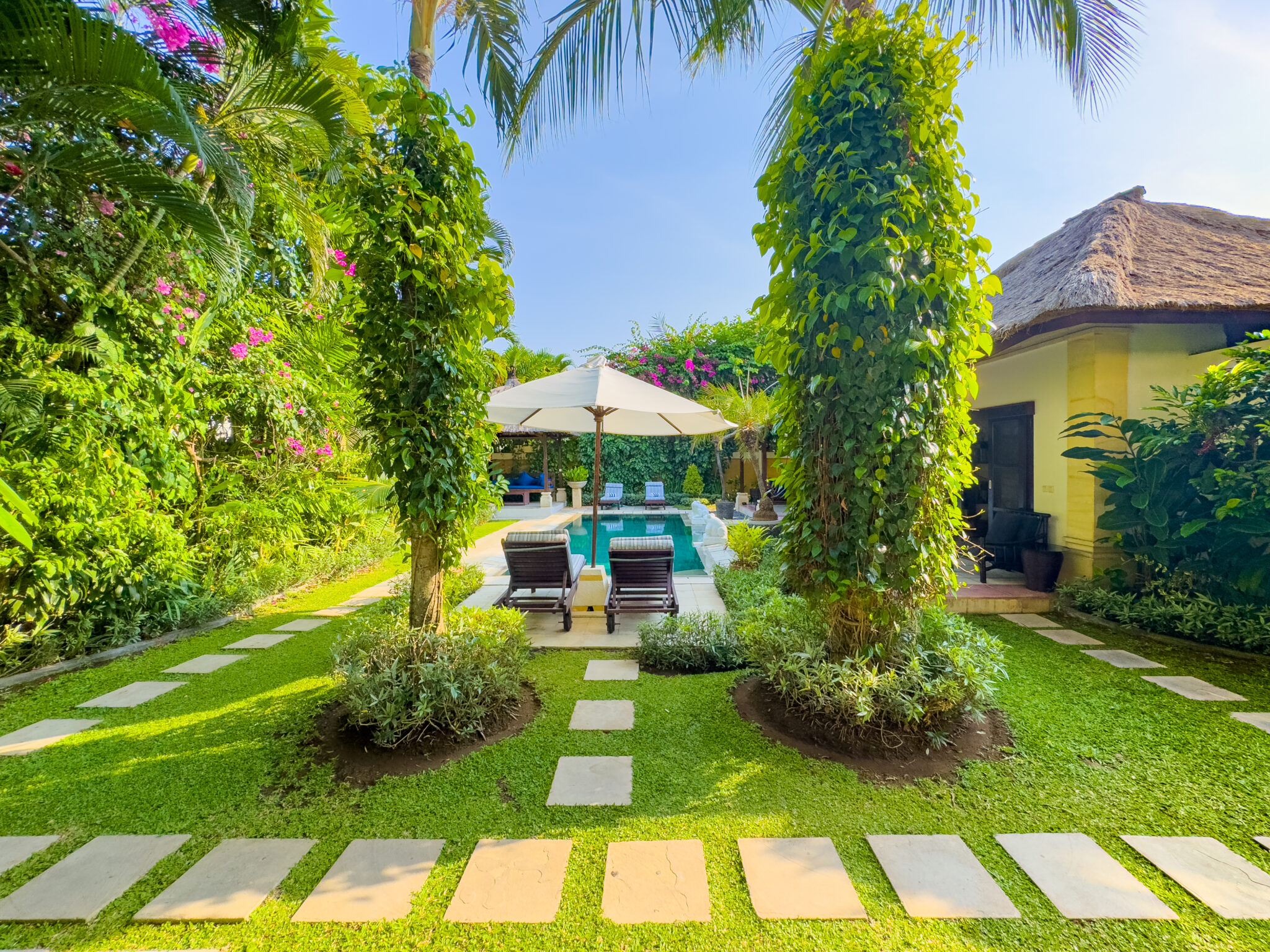 Manicured tropical garden pathway and green lawn surrounding the pool area at Villa Arjuna Seminyak by Villa Bugis villa Seminyak.