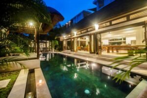 Open living pavilion glowing at dusk beside the private pool at Villa Damai Seminyak, Bali