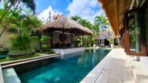 Poolside bale daybed and tropical garden beside the private pool at Villa Damai Seminyak, Bali
