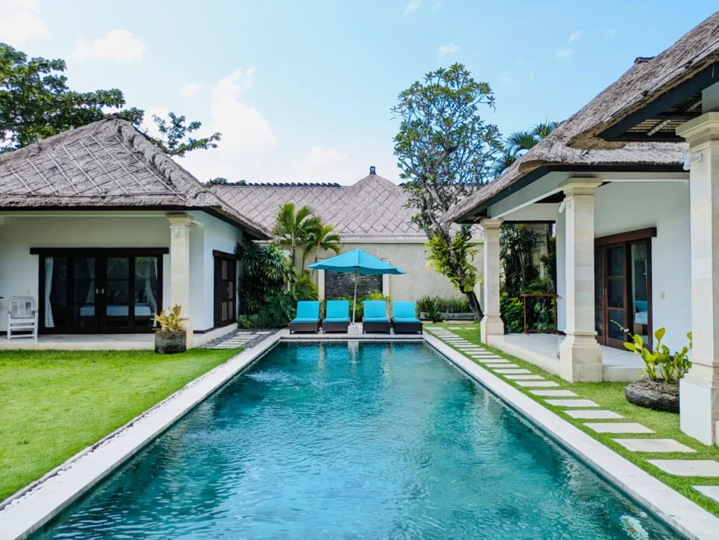 Luxury 5-bedroom villa in Seminyak featuring a private pool, poolside loungers, tropical garden, and a spacious outdoor area.
