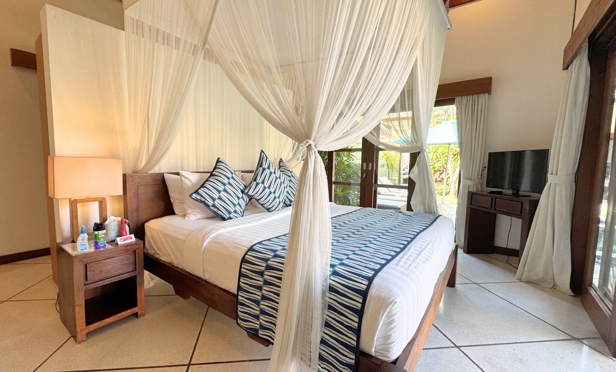 Interior design of bedroom 1 at Villa Darma Seminyak by Villa Bugis Seminyak villas, featuring a romantic canopy net and air conditioning.