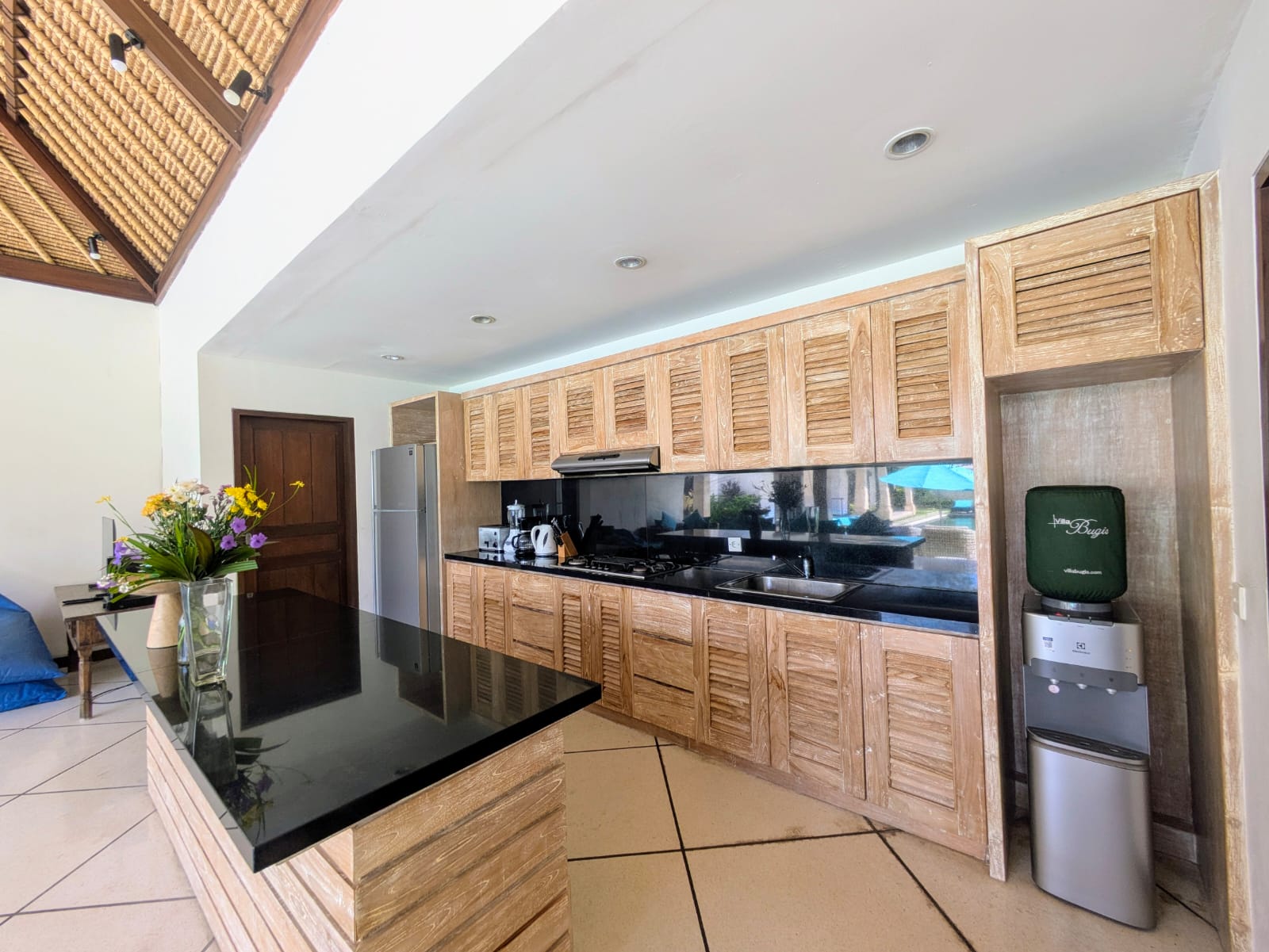 Clean fully-fitted kitchen and minimalist island bar at Villa Darma Seminyak by Villa Bugis, offering home-style cooking convenience in Seminyak villas.