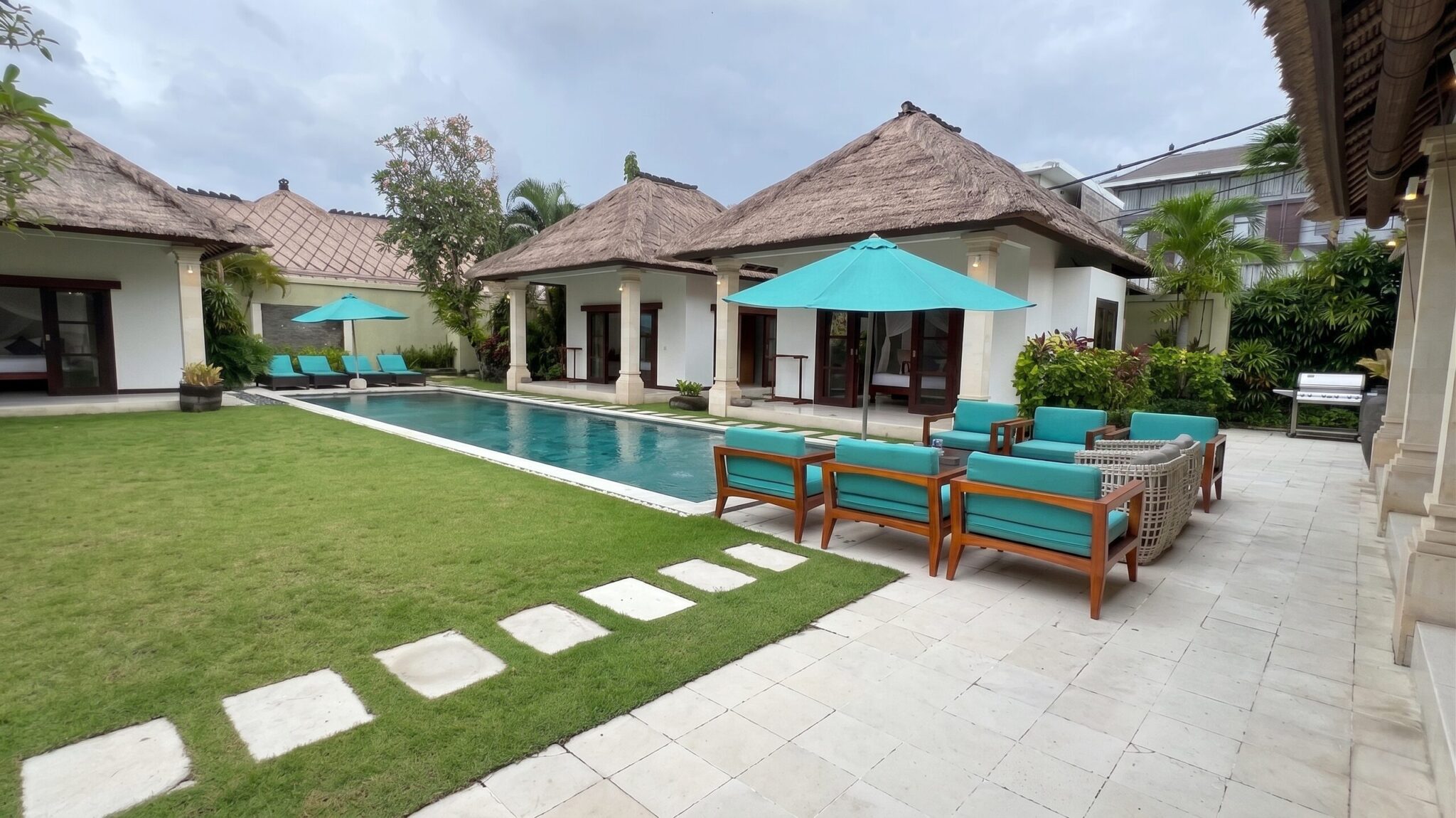 Poolside loungers and a stepping-stone path through tropical landscaping at Villa Darma Seminyak by Villa Bugis villa Seminyak.
