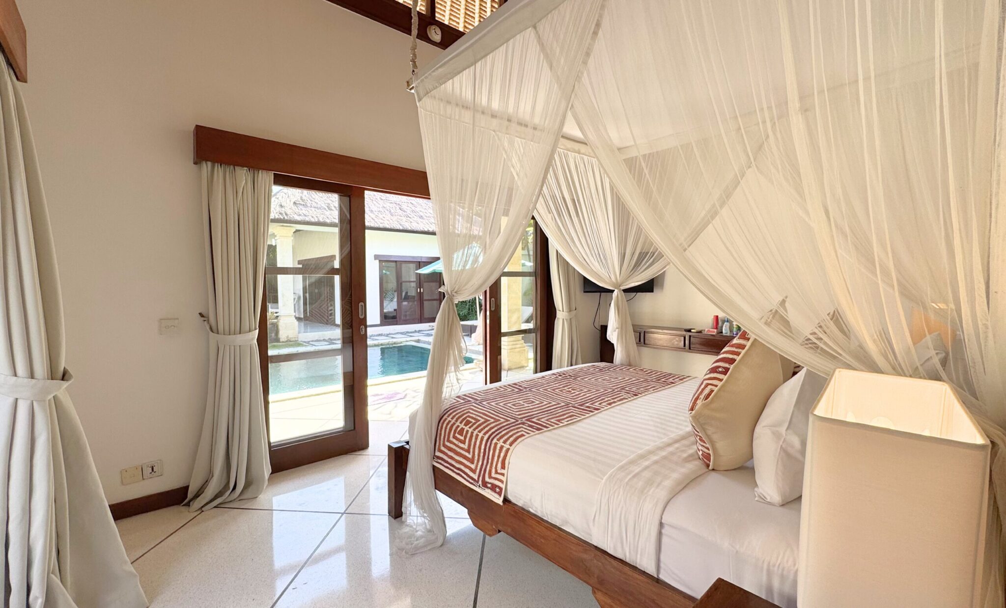 Large comfortable king bed with natural lighting and pool views in bedroom 2 at Villa Darma Seminyak by Villa Bugis, a highly recommended Seminyak villas choice.