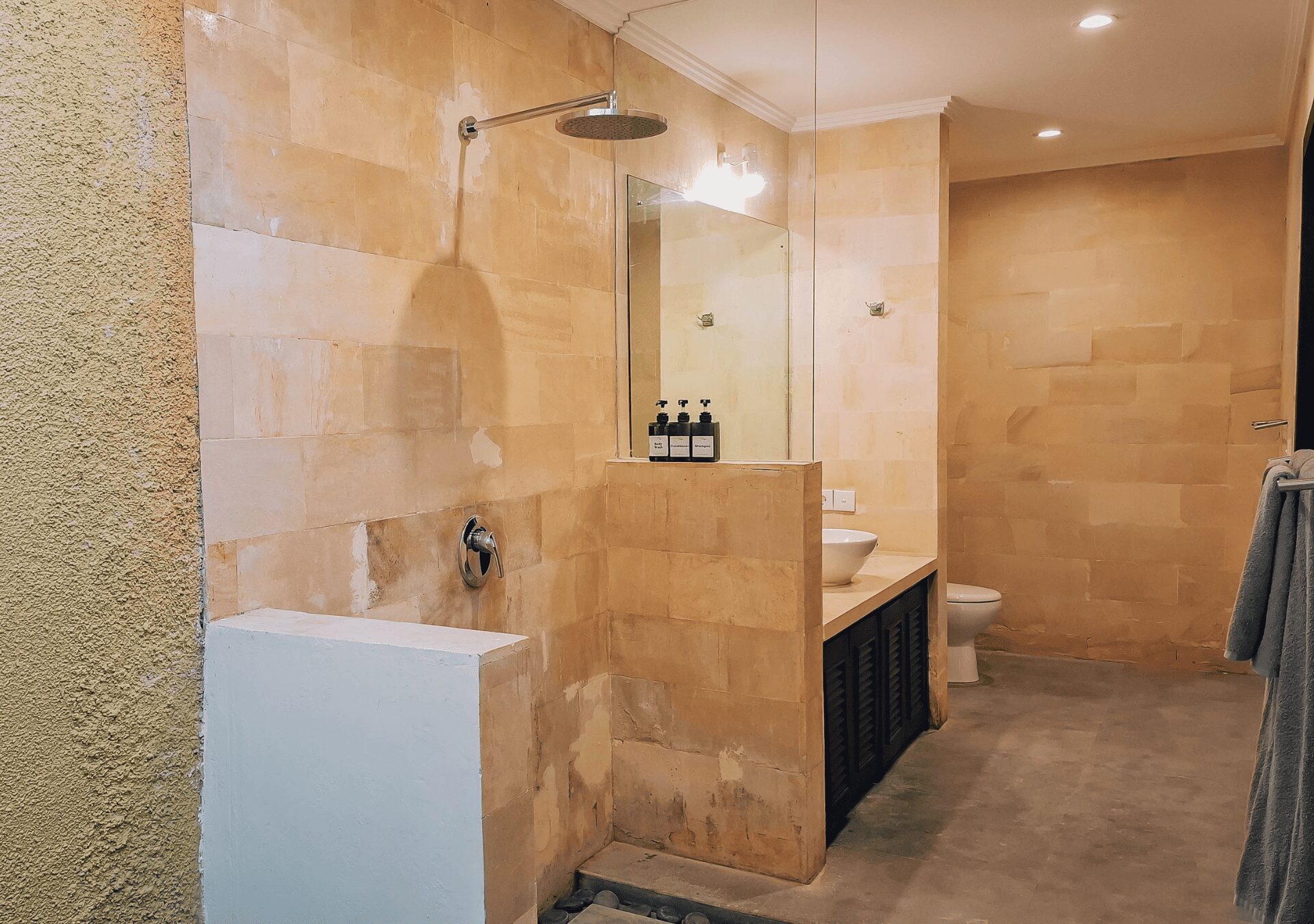 Well-lit vanity mirror and stone textures in the bathroom of bedroom 3 at Villa Gembira Seminyak by Villa Bugis Seminyak villas.