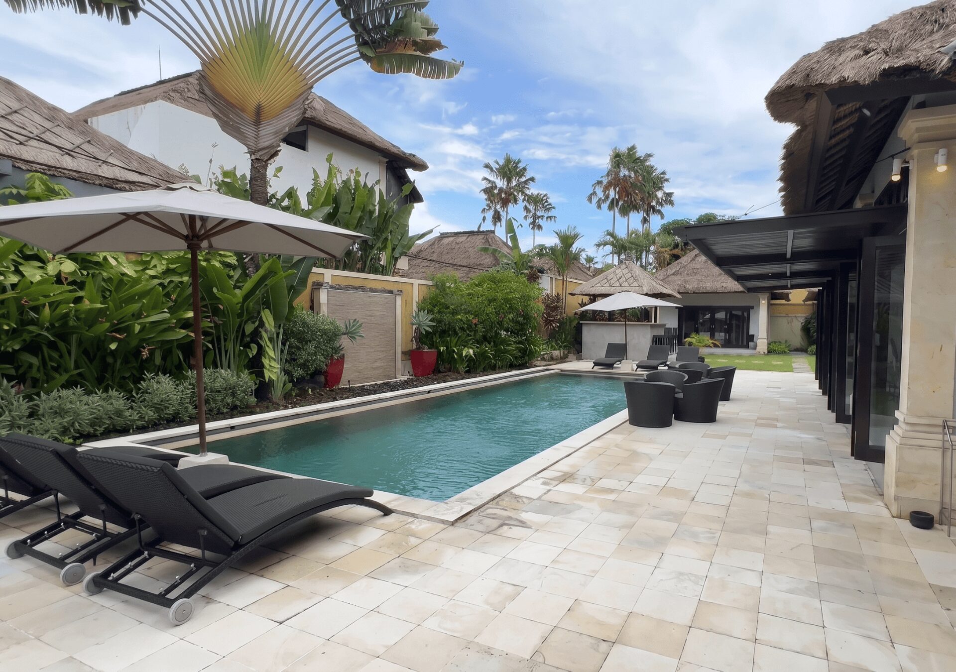 Pristine private outdoor swimming pool surrounded by tropical plants and sun lounges at Villa Gembira Seminyak by Villa Bugis, a luxury villa Seminyak.