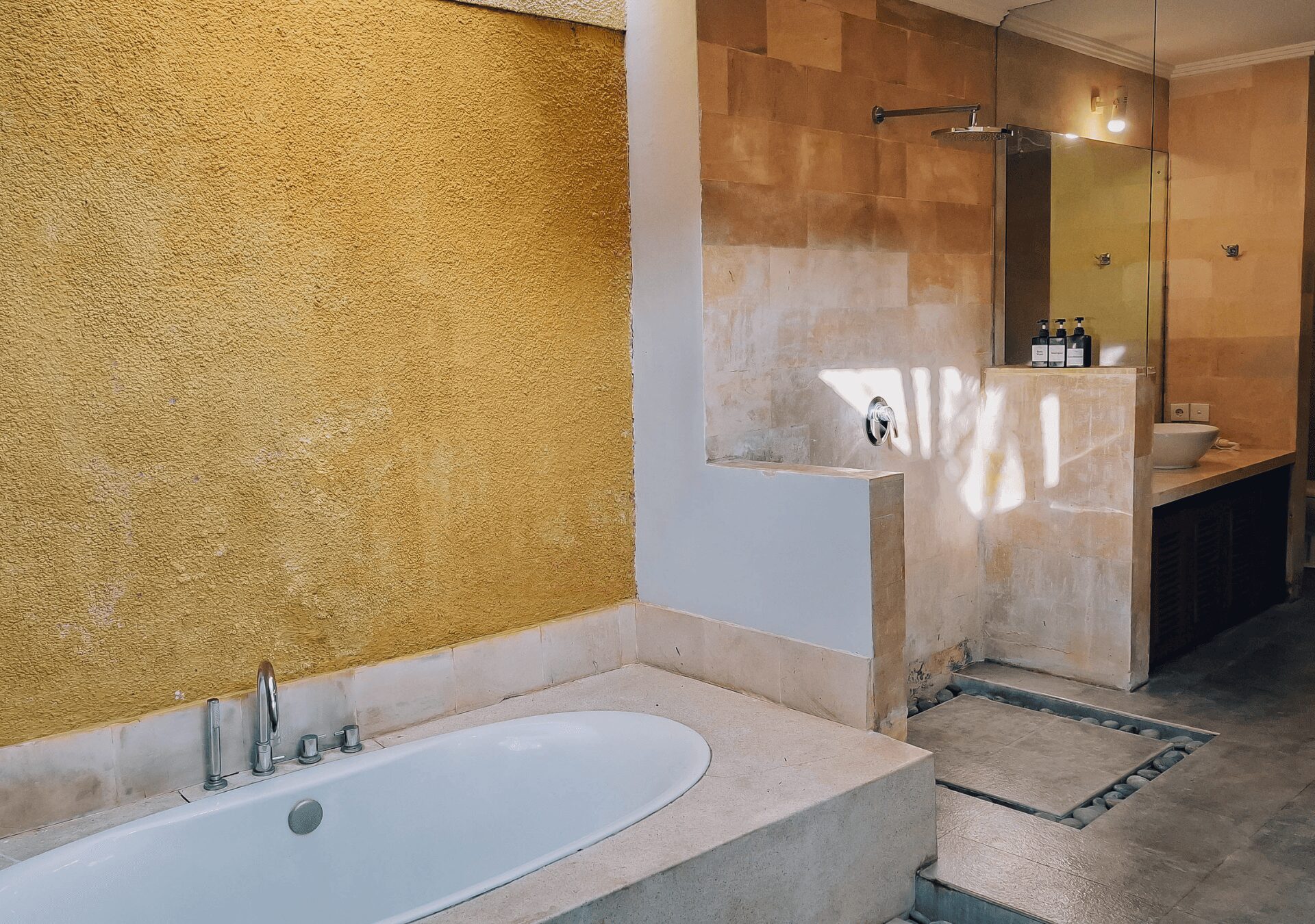 Tropical semi-outdoor ensuite bathroom with a soaking bathtub attached to bedroom 1 at Villa Gembira Seminyak by Villa Bugis, offering a unique villa Seminyak experience.