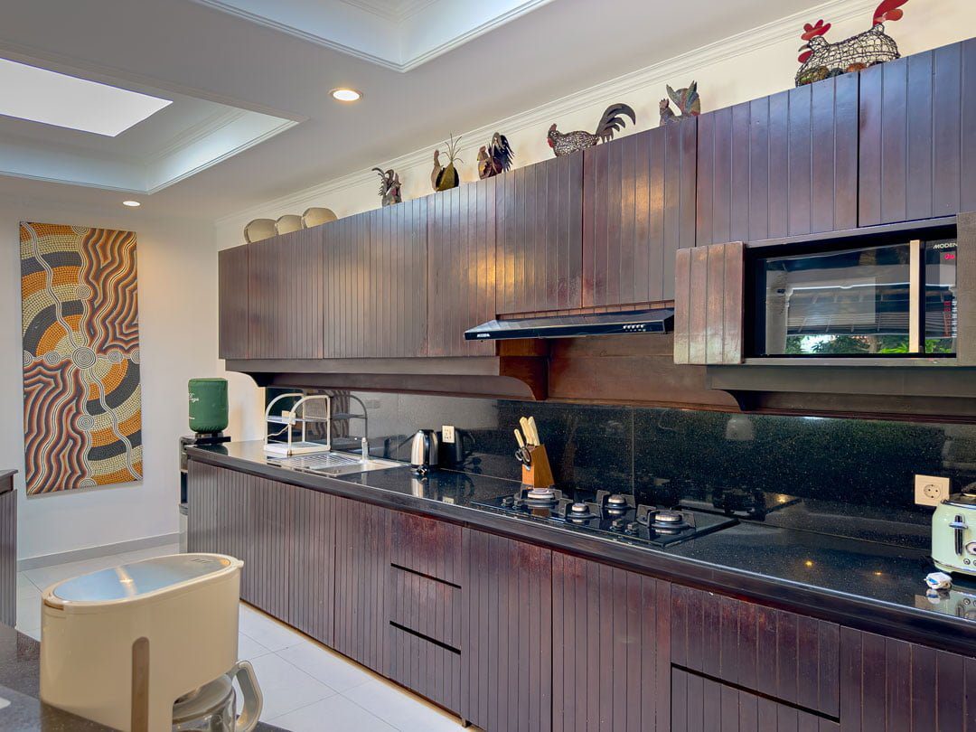 Clean fully-fitted wooden kitchen and minimalist dining area at Villa Ginger Seminyak by Villa Bugis, offering home-style convenience in Seminyak villas.