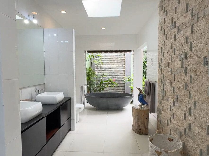 Clean modern vanity, stylish mirror, and a soaking bathtub inside the master bathroom at Villa Ginger Seminyak by Villa Bugis Seminyak villas.