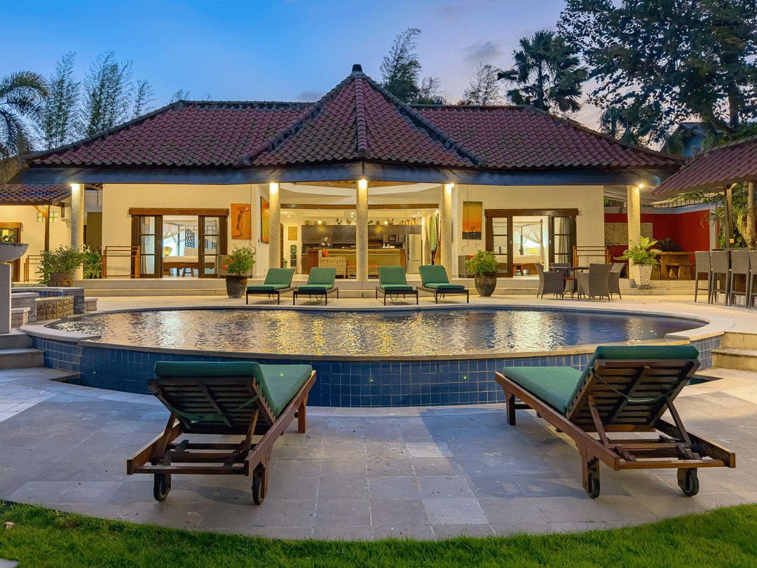 Cozy dusk scene of the outdoor pool deck at Villa Ginger Seminyak by Villa Bugis Seminyak villas, presenting a peaceful evening vibe.