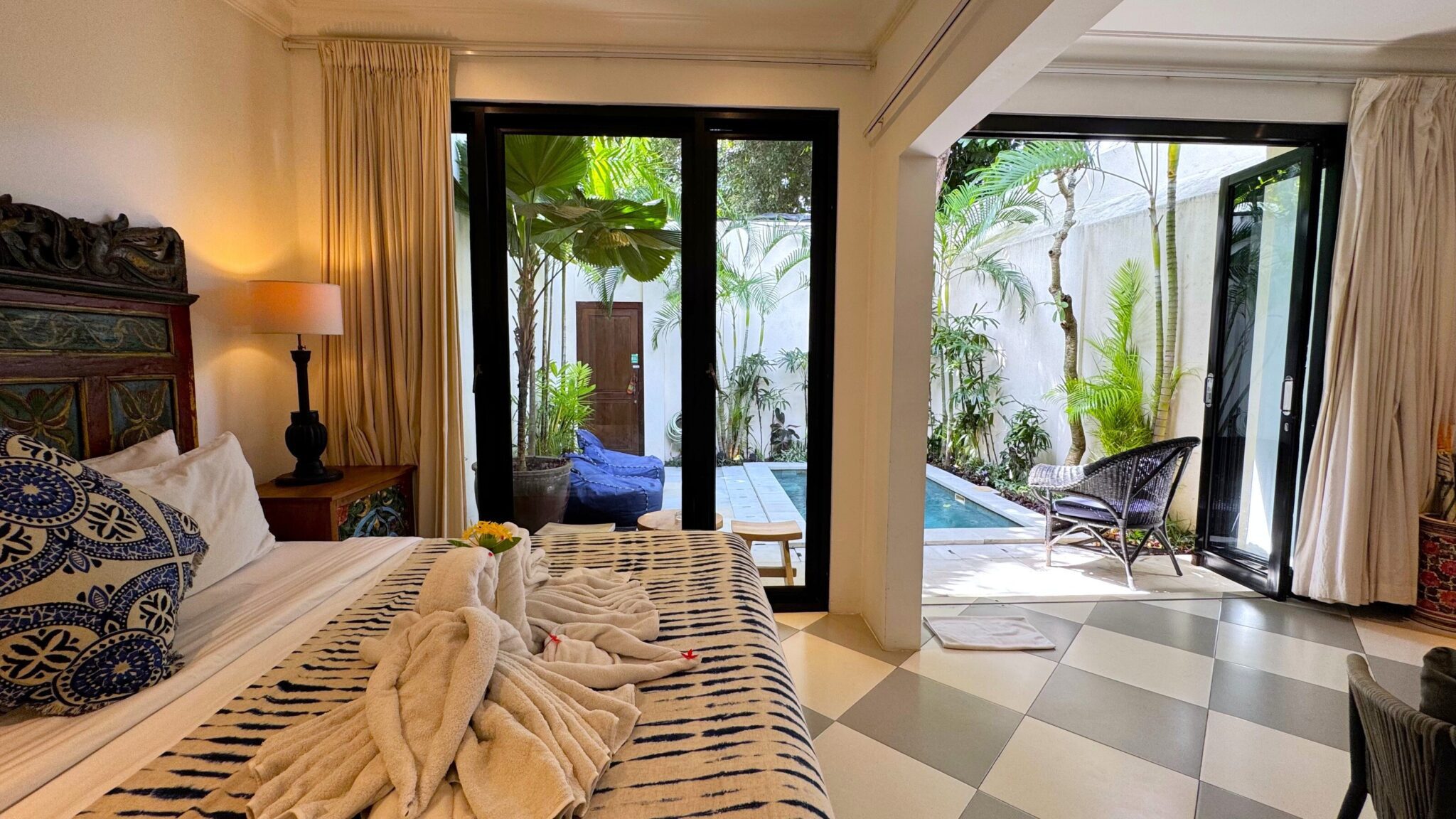 Cozy bedroom interior with air conditioning, warm lighting, and a direct view to the private pool at Villa Ibu Dua Seminyak by Villa Bugis Seminyak villas.