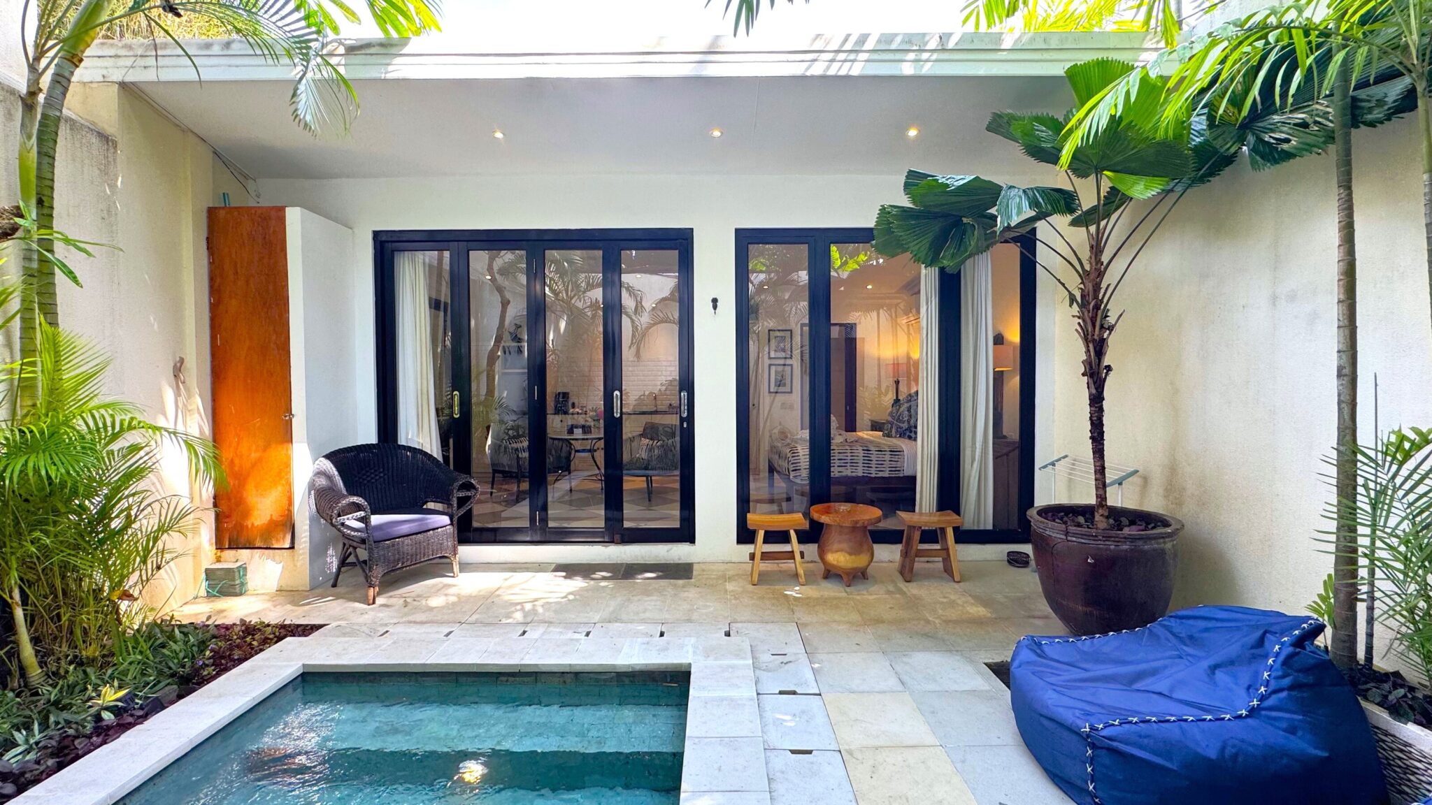 Sunny daytime view of the poolside lounge deck and tropical greenery at Villa Ibu Dua Seminyak by Villa Bugis Seminyak villas.