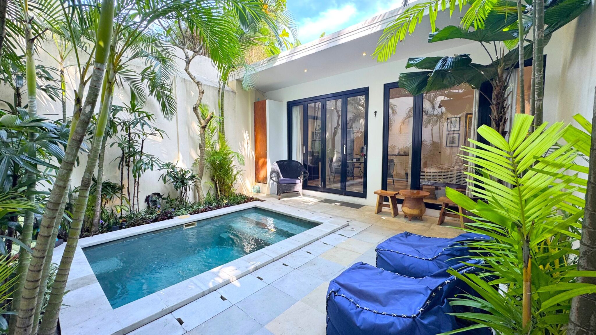 Private outdoor swimming pool surrounded by a lush tropical garden and sun loungers at Villa Ibu Dua Seminyak by Villa Bugis, a romantic 1-bedroom villa Seminyak.