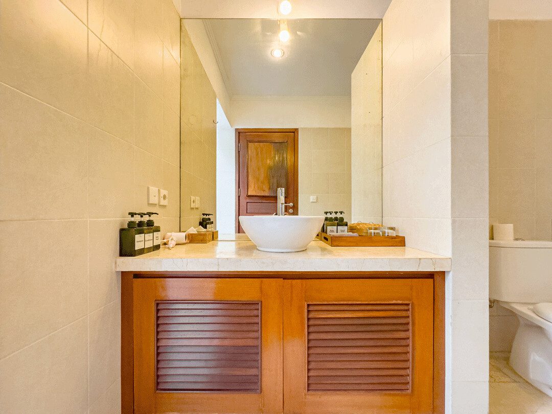 Pristine shower area enclosed by natural stone textures and plants in the bathroom of bedroom 4 at Villa Jaclan Seminyak by Villa Bugis Seminyak villas.