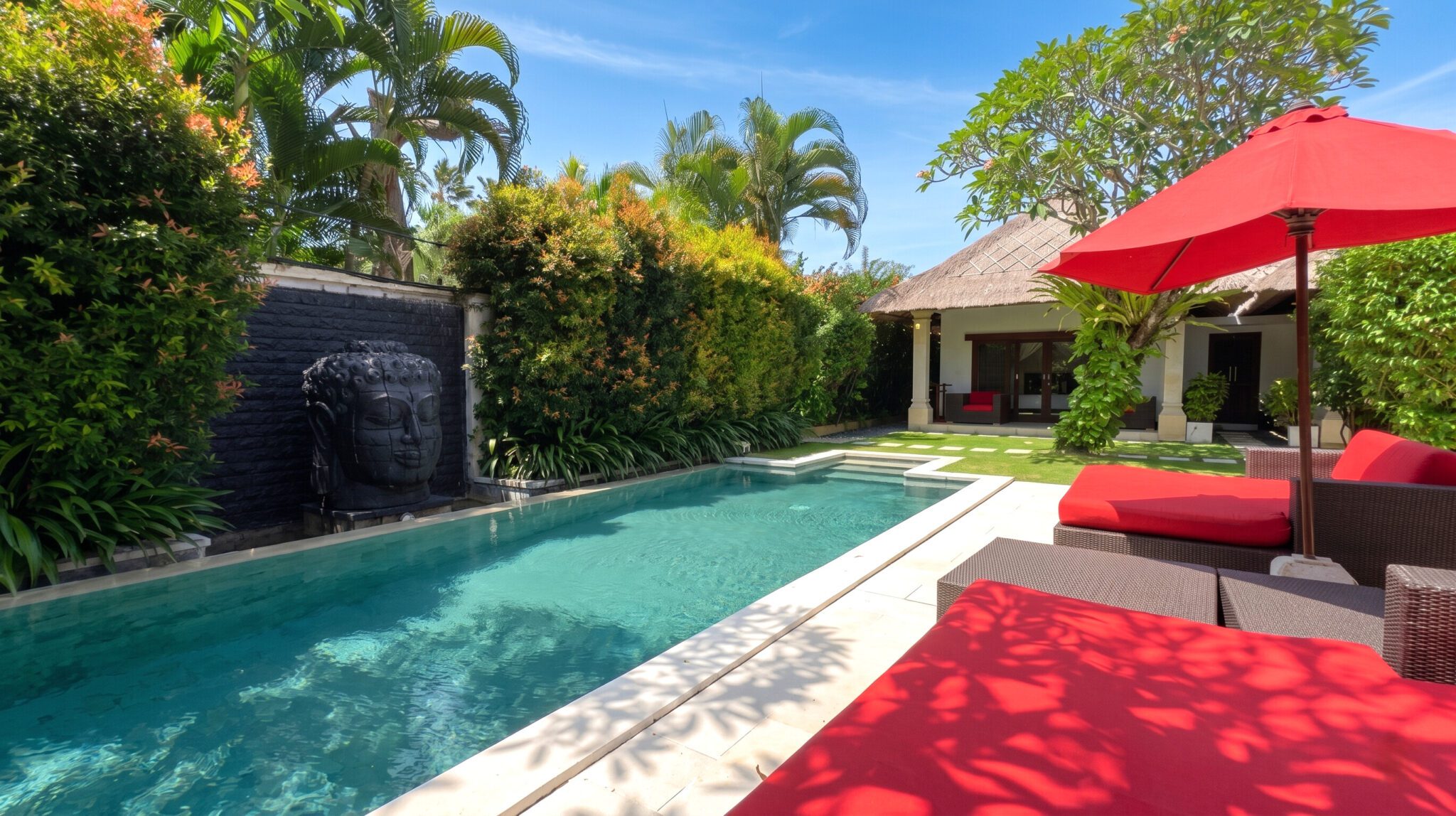 Pristine private outdoor swimming pool at Villa Jaclan Seminyak by Villa Bugis, a luxury villa Seminyak featuring stylish sun loungers and a lush tropical garden.