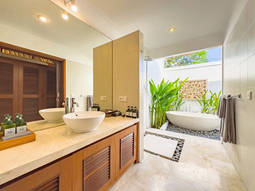 Elegant stone design, minimalist vanity, and a soaking bathtub inside the bathroom of bedroom 2 at Villa Jaclan Seminyak by Villa Bugis Seminyak villas.