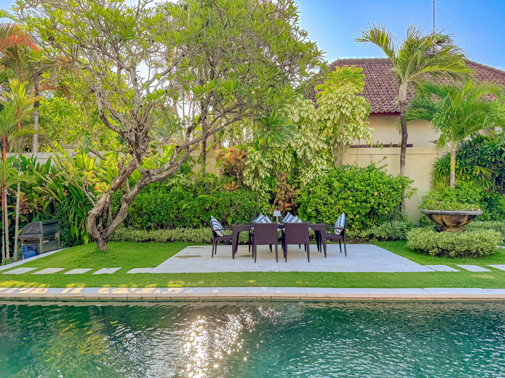 Sunny landscape view of the lush manicured lawn and private pool at Villa Kebun Seminyak by Villa Bugis Seminyak villas.