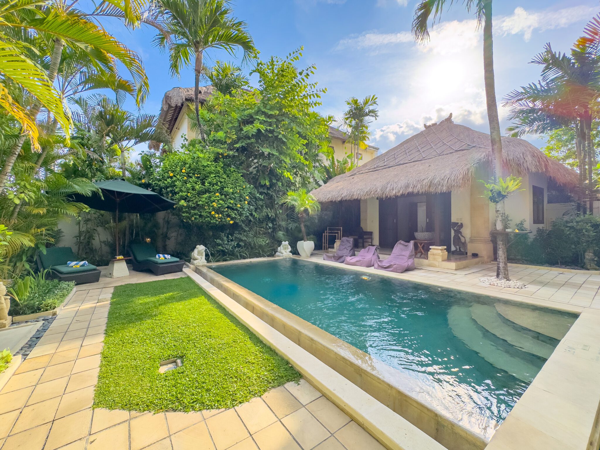 Sunny landscape of the poolside relaxation area at Villa Krisna Seminyak by Villa Bugis, ideal for family vacations in a villa Seminyak.