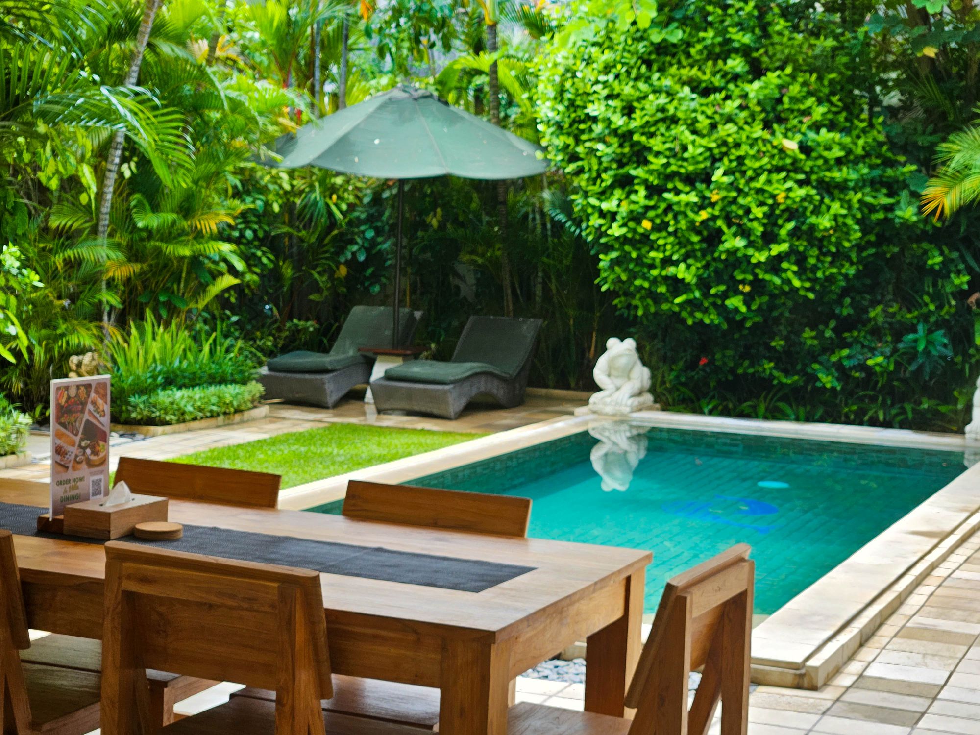 Open-air living room pavilion with plush sofa seating facing the private pool at Villa Krisna Seminyak by Villa Bugis villa Seminyak.
