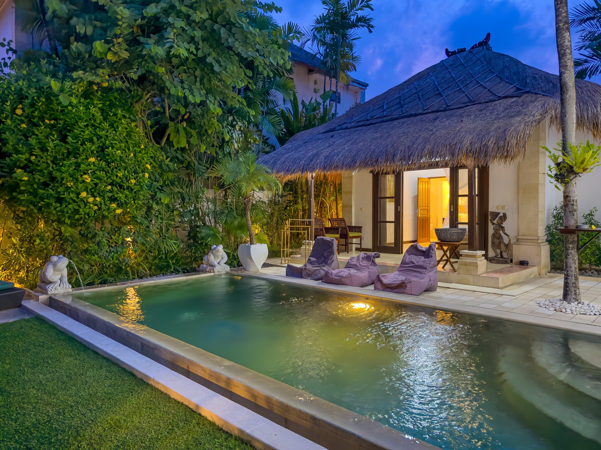 Cozy night view of the illuminated poolside patio and garden at Villa Krisna Seminyak by Villa Bugis Seminyak villas.