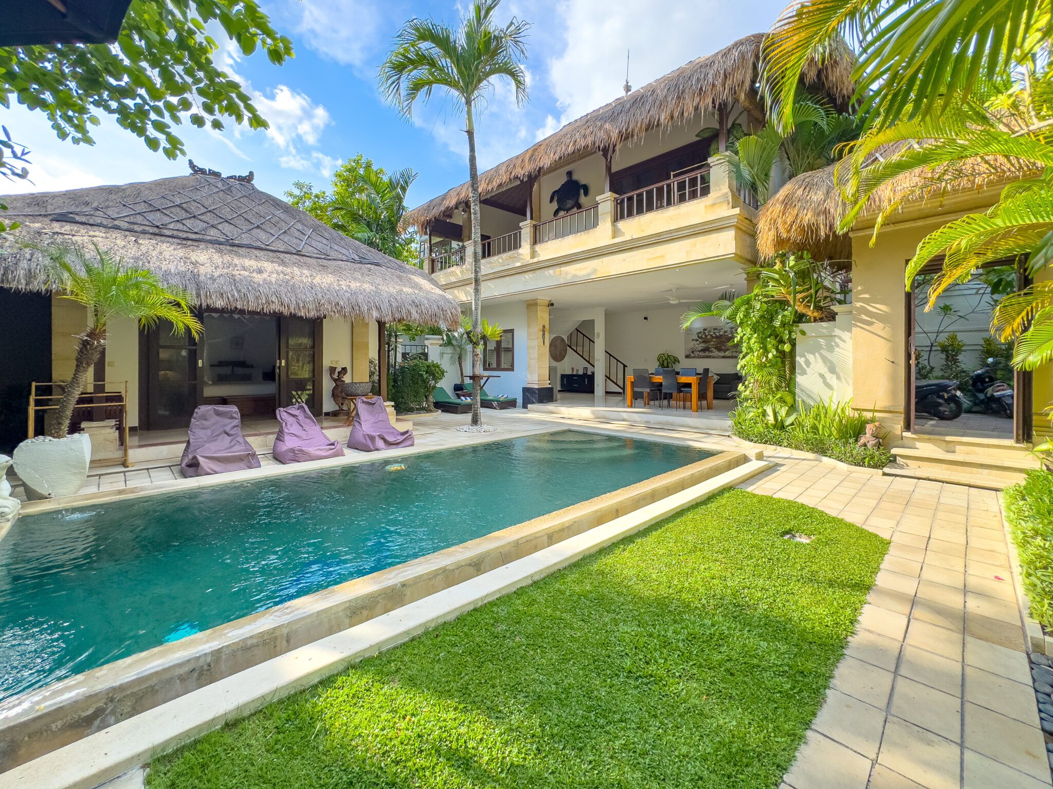 Bright daytime view of the main pool deck and lush tropical garden at Villa Krisna Seminyak by Villa Bugis Seminyak villas.