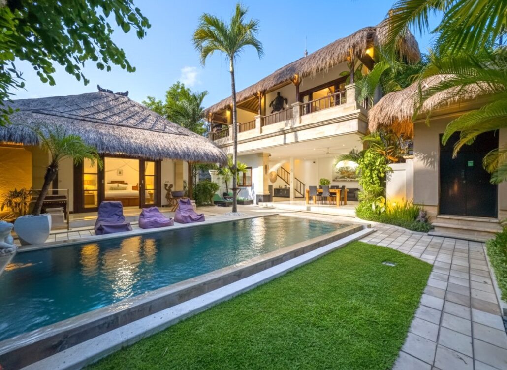 Clear private swimming pool with wooden decking and tropical plants at Villa Krisna Seminyak