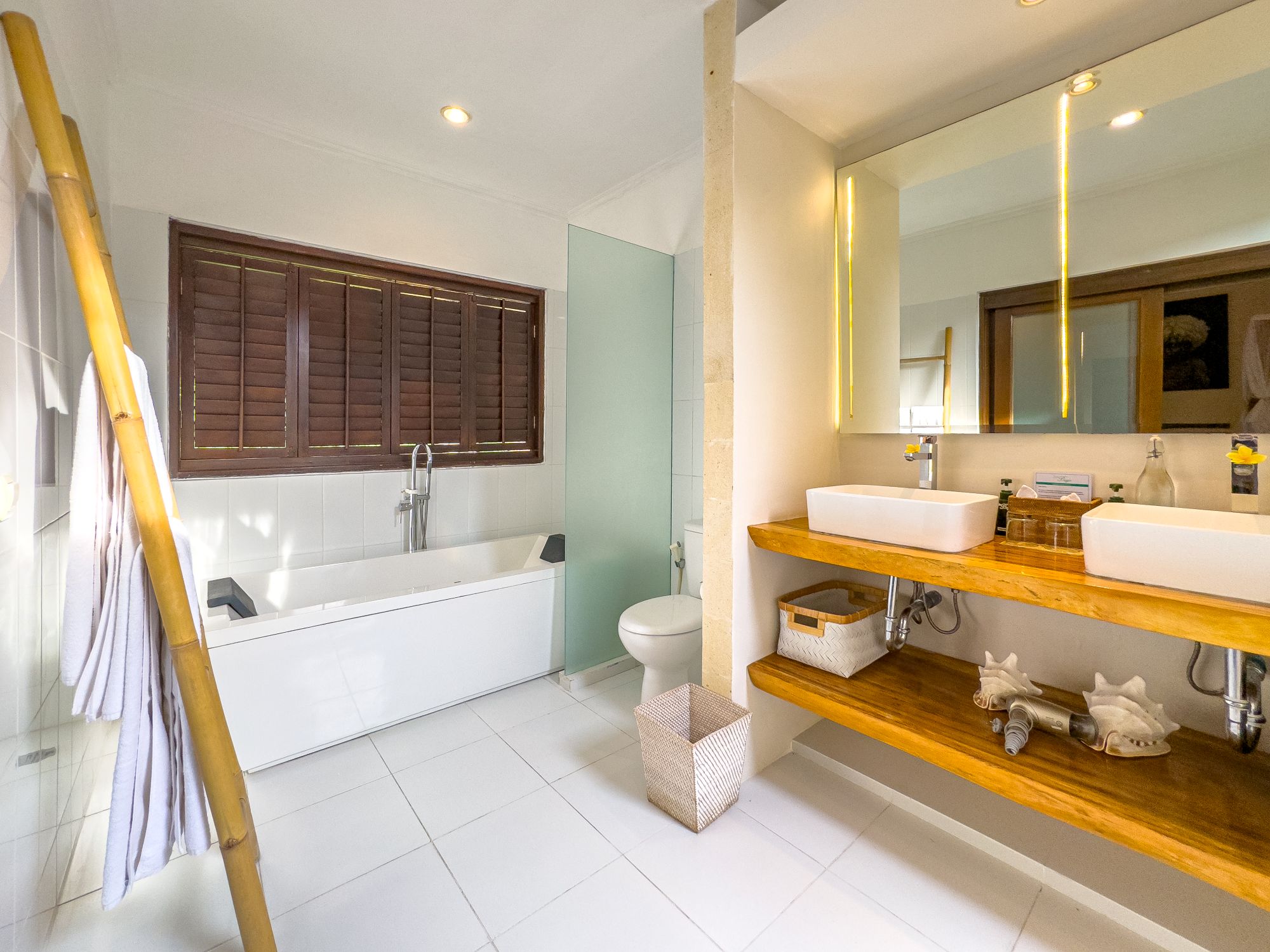 Clean modern vanity, stone basin, and a soaking bathtub in the master bathroom at Villa Nakula Seminyak by Villa Bugis Seminyak villas.