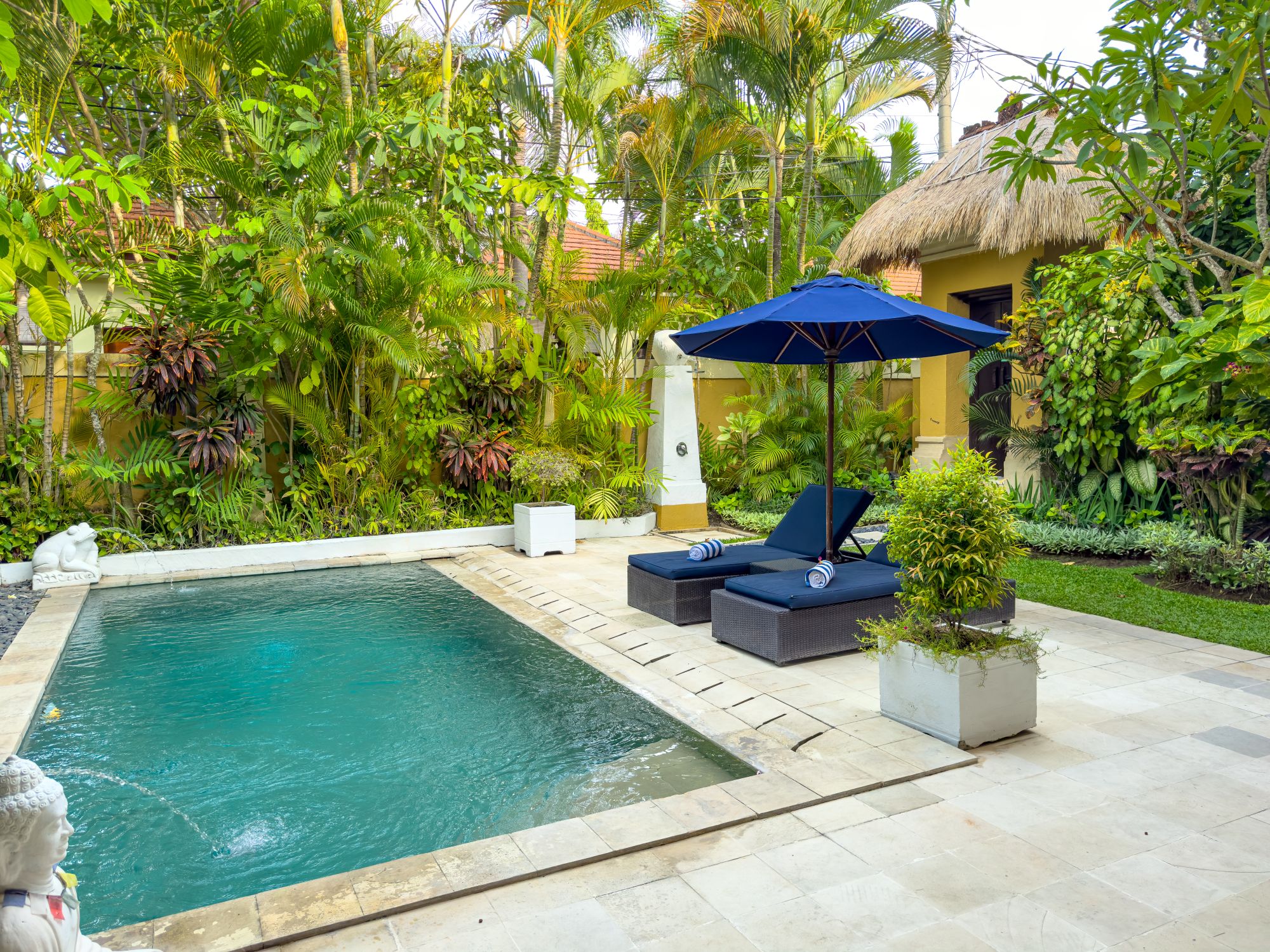 Pristine private outdoor swimming pool surrounded by sun loungers and tropical plants at Villa Nakula Seminyak by Villa Bugis, a luxury villa Seminyak.