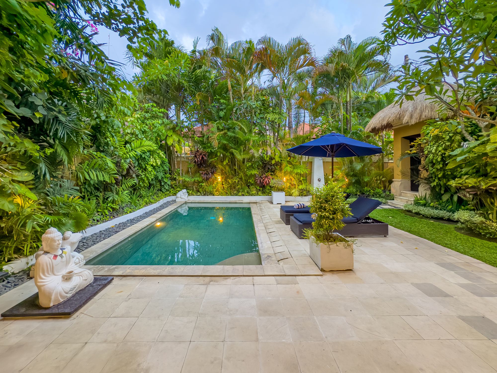 Sunny landscape of the poolside relaxation area at Villa Nakula Seminyak by Villa Bugis, ideal for family vacations in a villa Seminyak.