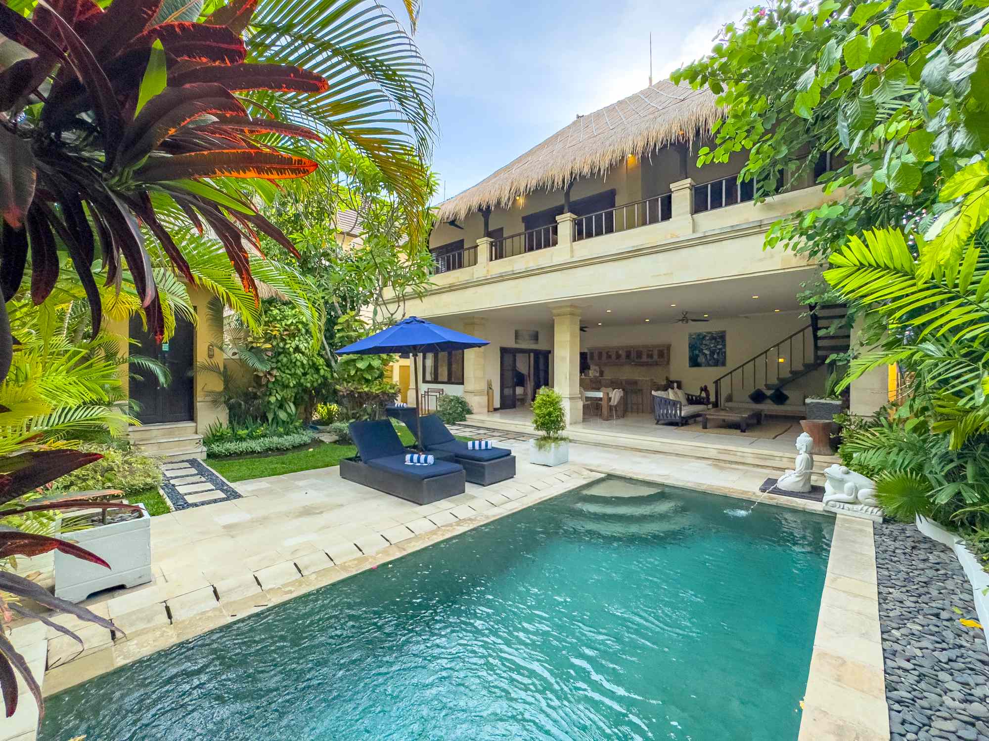 Bright daytime view of the main pool deck and lush tropical garden at Villa Nakula Seminyak by Villa Bugis Seminyak villas.