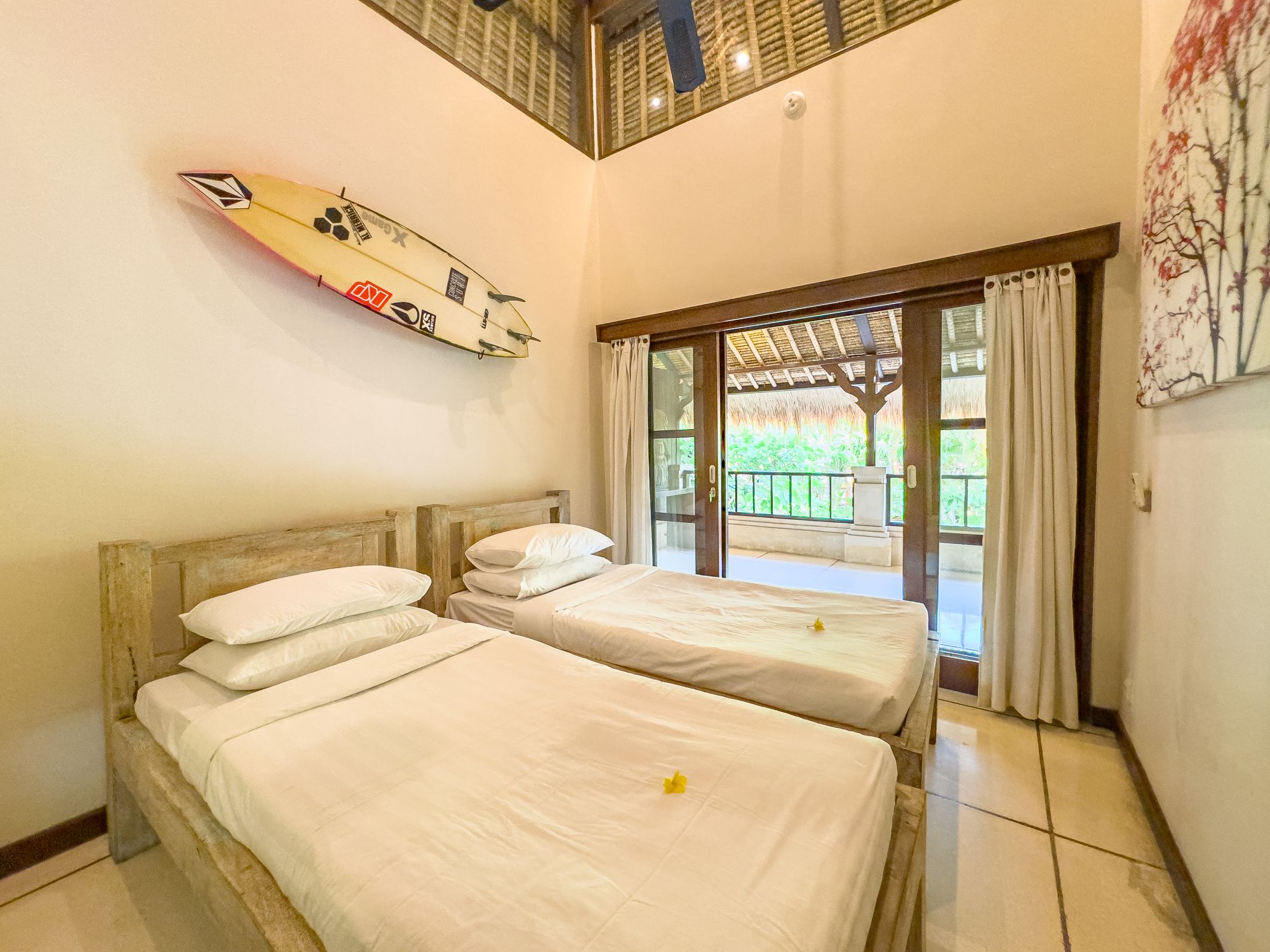 Airy twin bedroom with balcony access at Villa Nakula Seminyak by Villa Bugis Seminyak villas, equipped with air conditioning and comfortable double single beds.