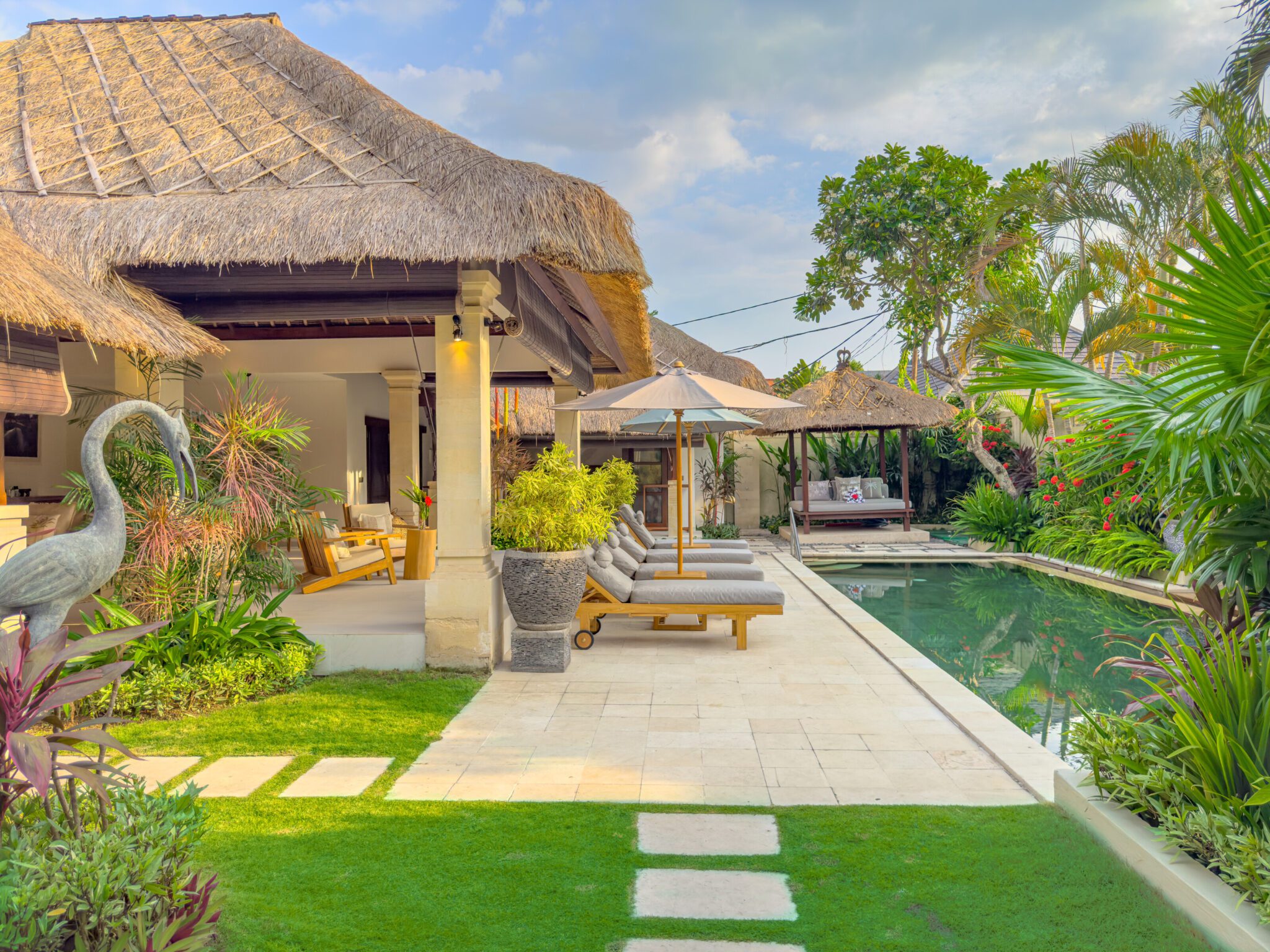 Bright daytime view of the spacious pool deck and vibrant tropical greenery at Villa Olive Seminyak by Villa Bugis Seminyak villas.