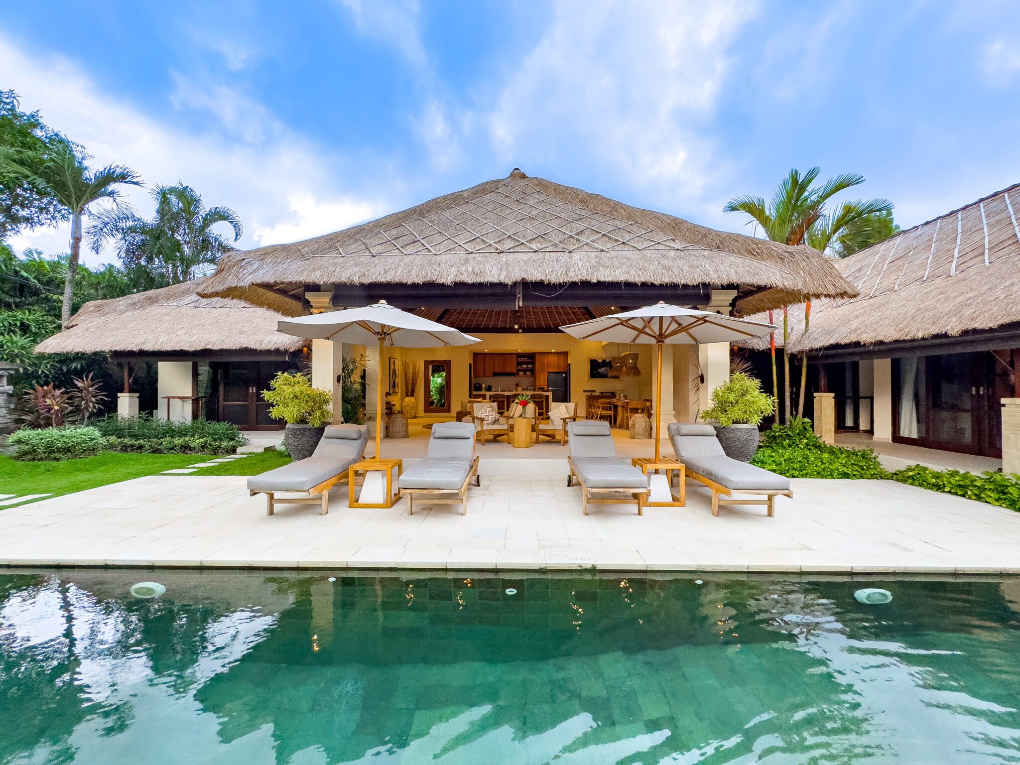 Sunlit private outdoor swimming pool surrounded by comfortable sun loungers and a lush tropical garden at Villa Olive Seminyak by Villa Bugis, a luxury villa Seminyak.