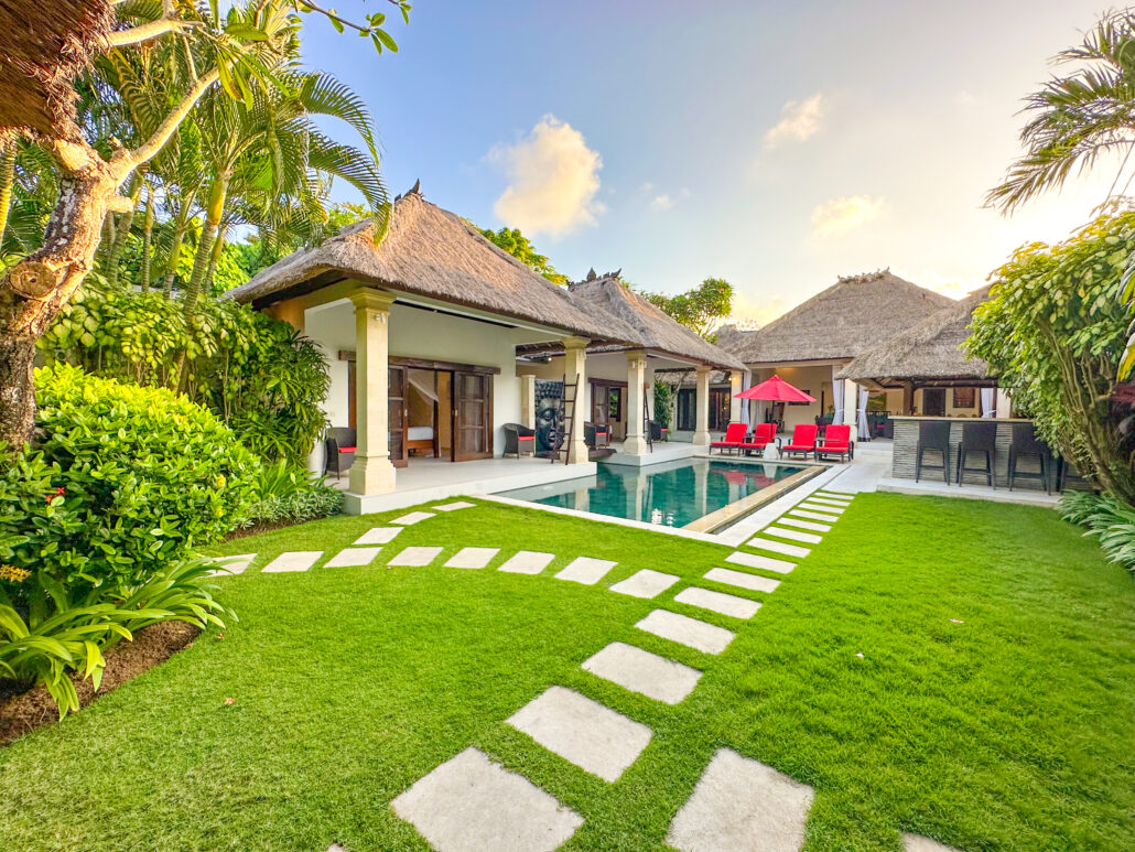 Clear private swimming pool with wooden decking and tropical plants at Villa Rama Seminyak